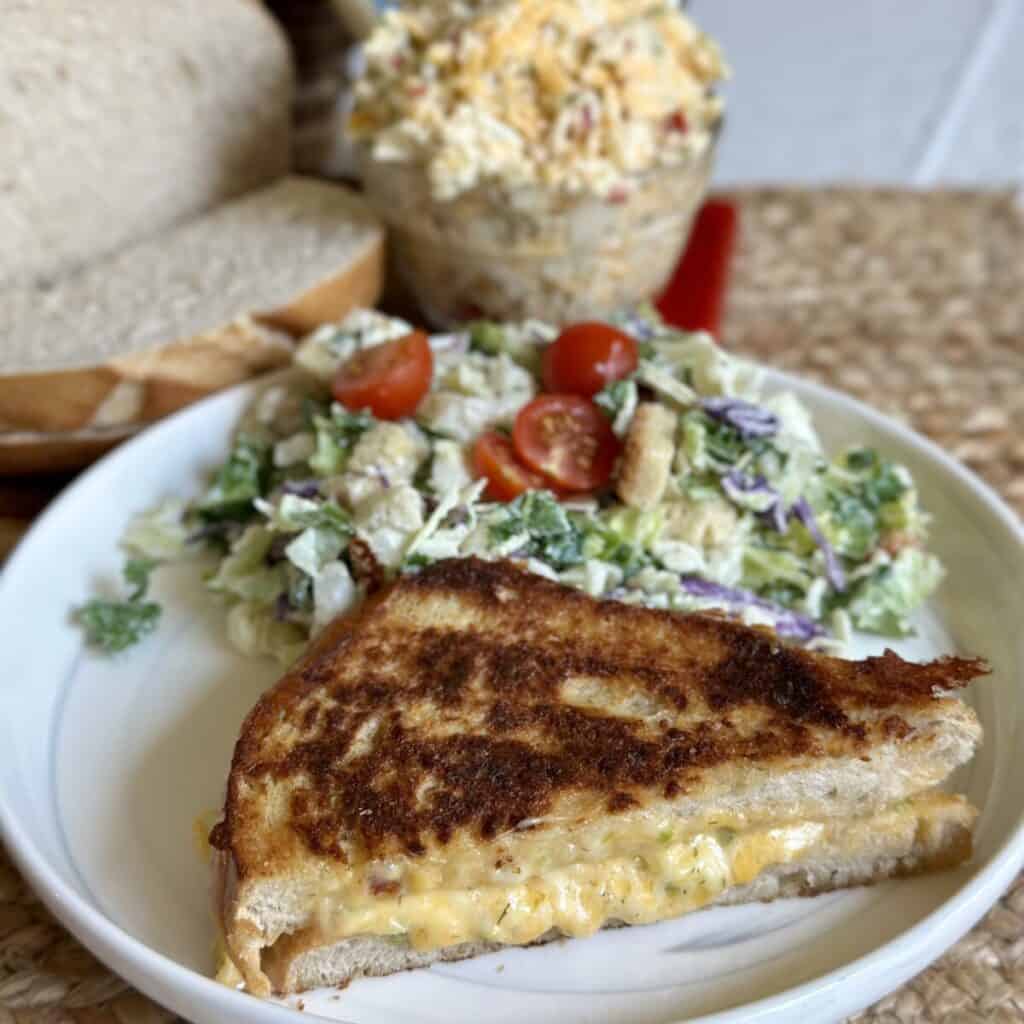 A pimento grilled cheese and salad on a plate.