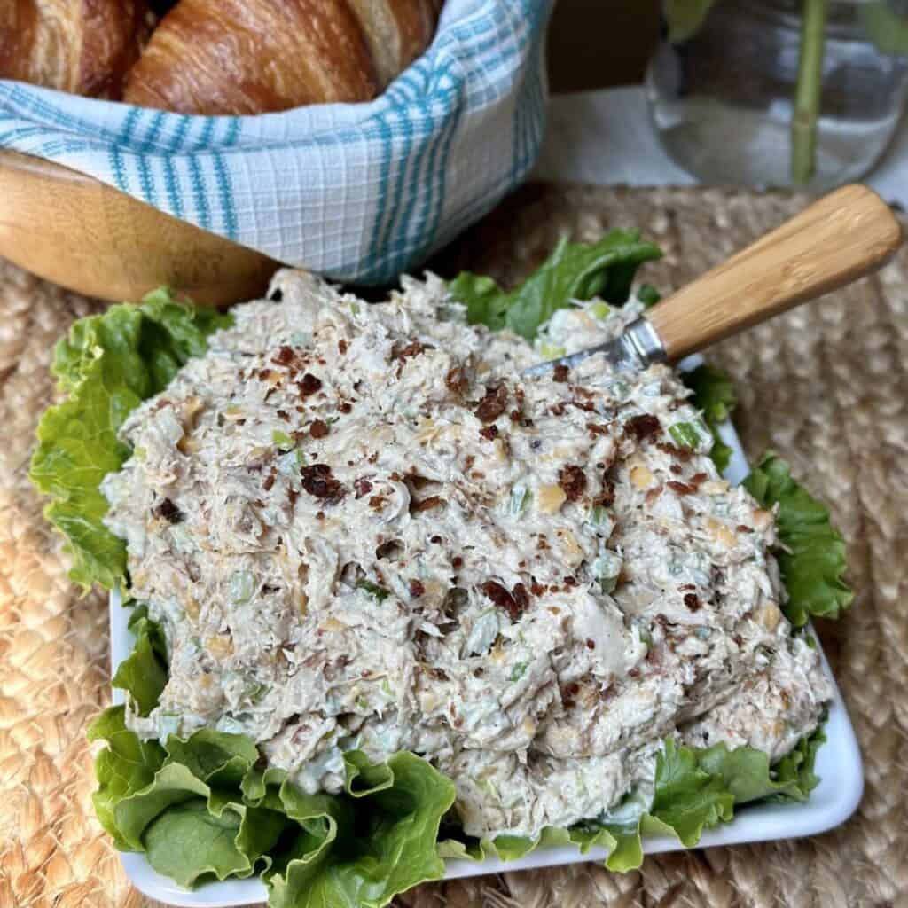 A bowl of chicken salad with a spreader.