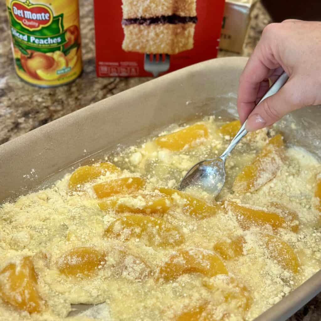 Mixing together cake mix and peaches in a 13x9 pan.