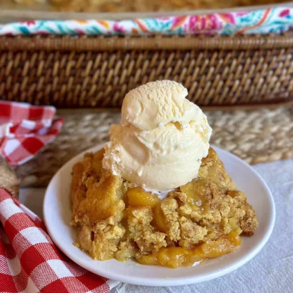 A saucer of peach cobbler and ice cream.