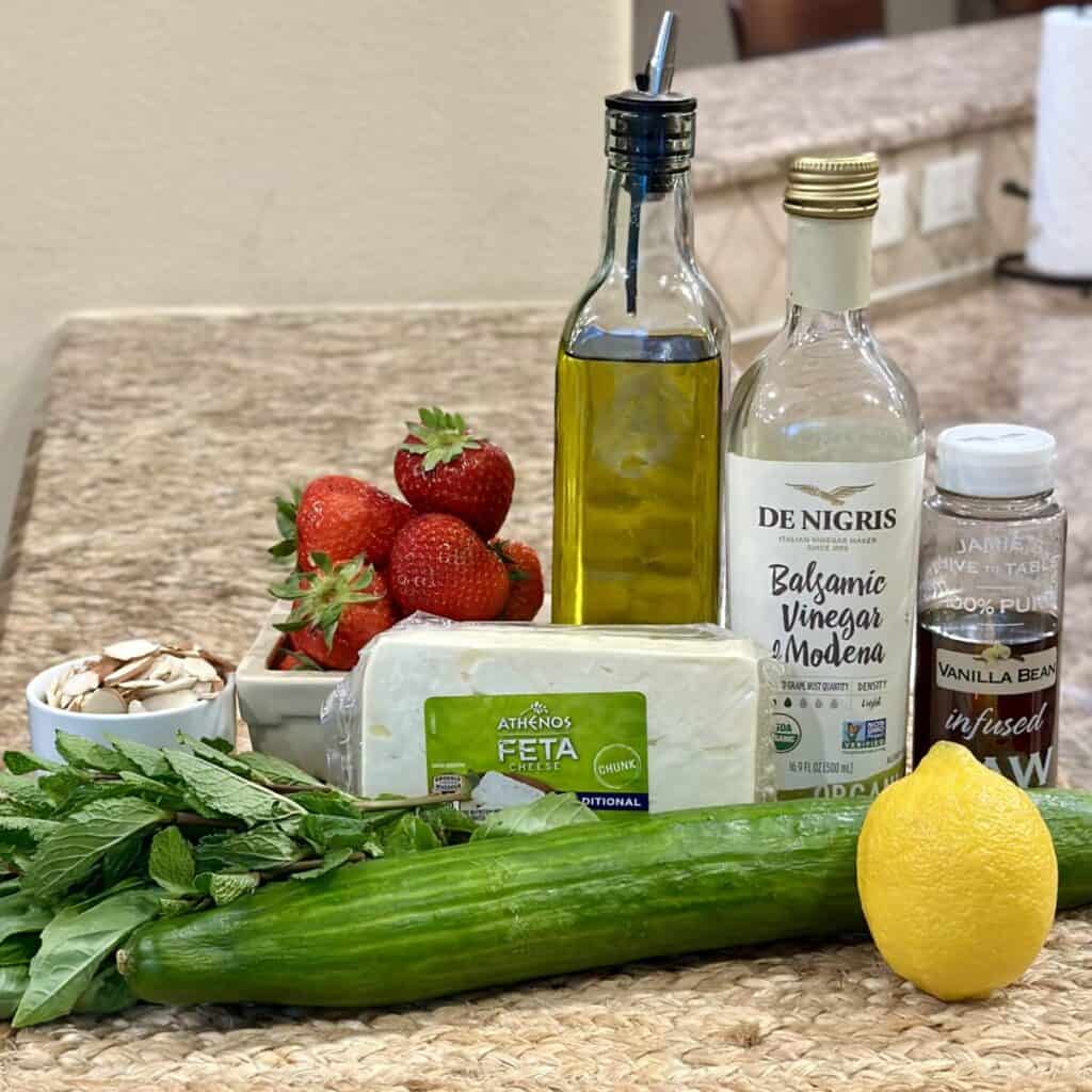 The ingredients to make a cucumber strawberry salad.