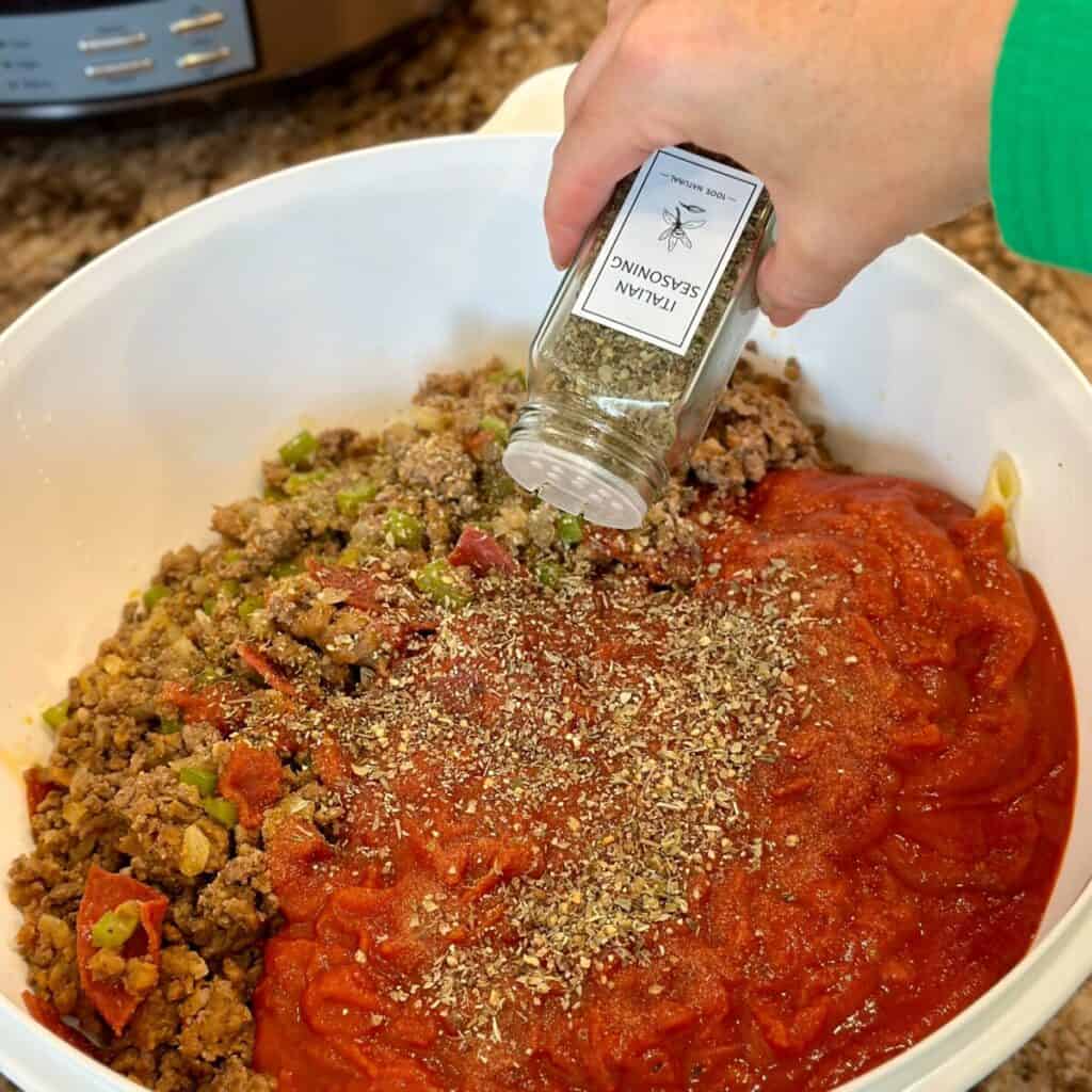 Adding Italian seasoning to a casserole filling.