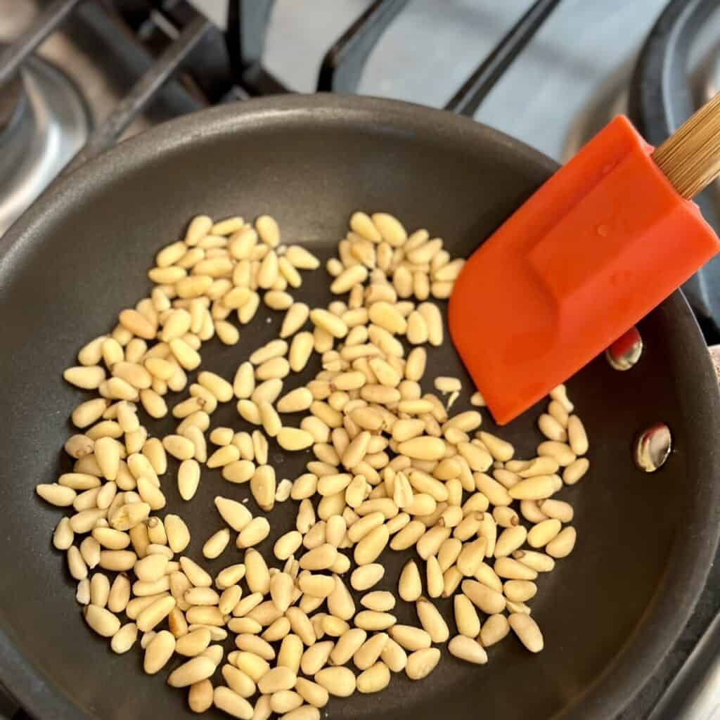 Toasting pine nuts in a skillet.