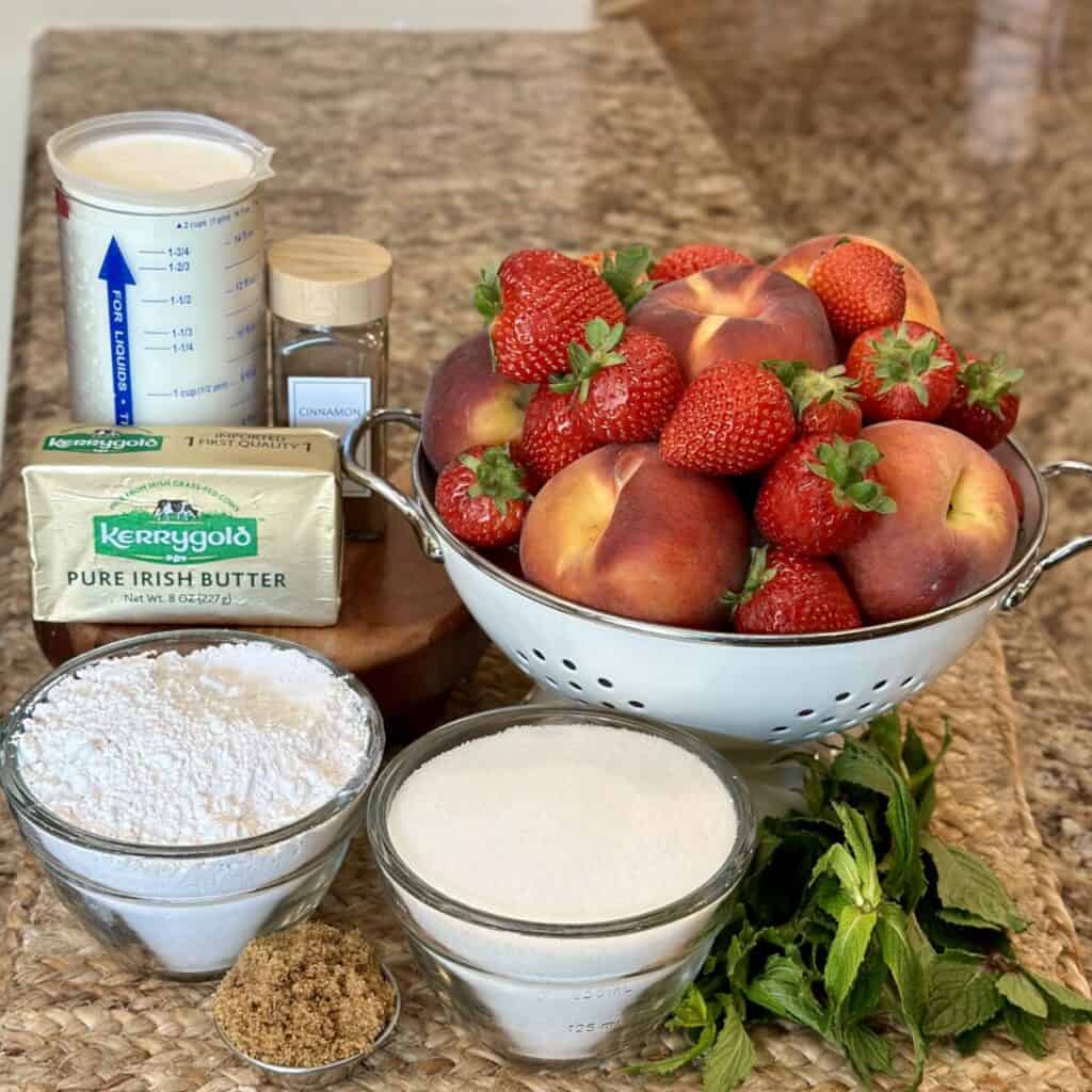 The ingredients to make a strawberry peach cobbler.