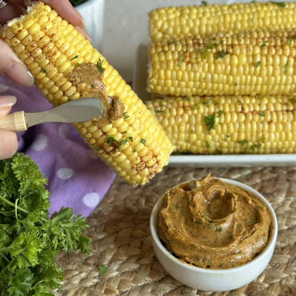 Spreading cajun butter on corn.