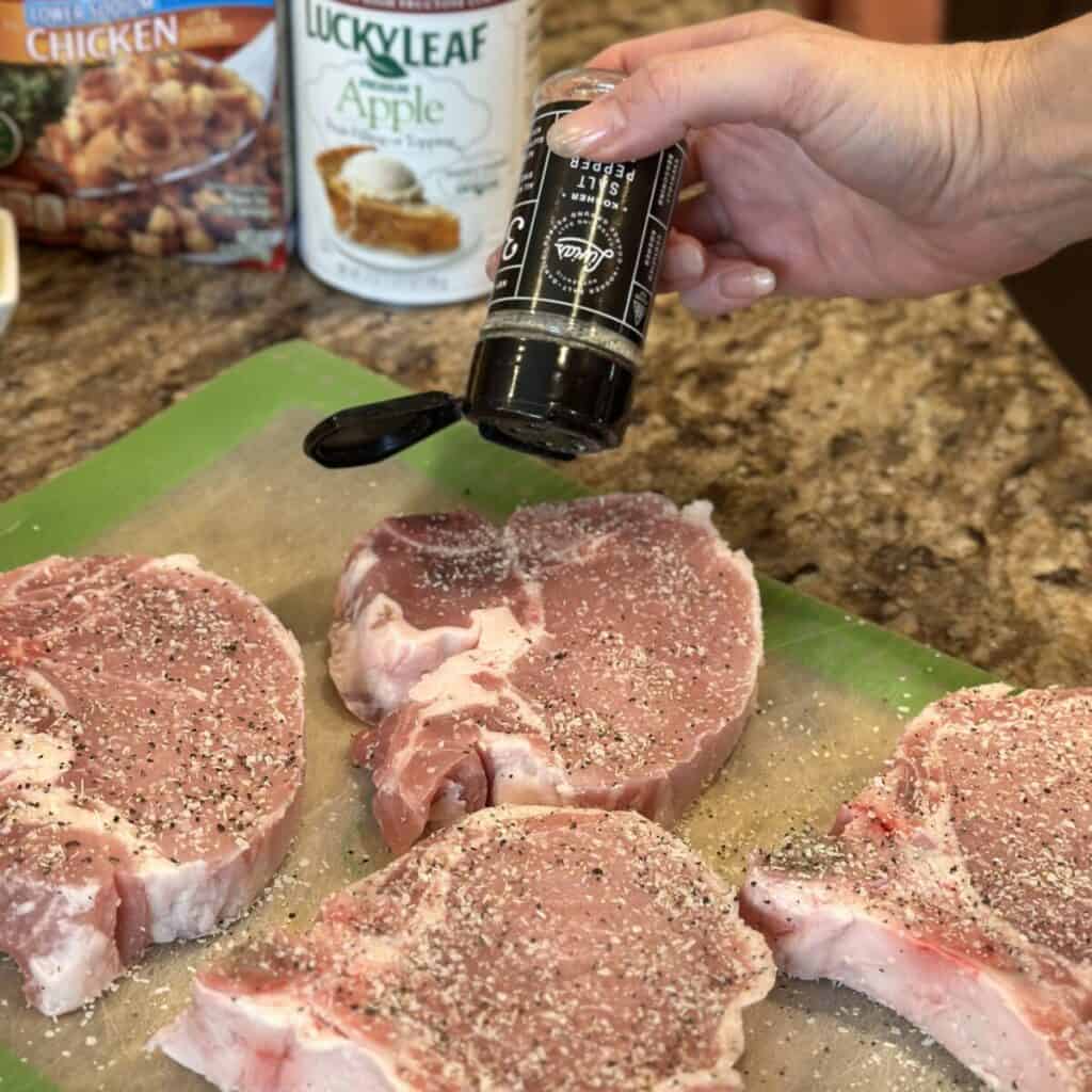 Seasoning pork chops with seasoning salt.