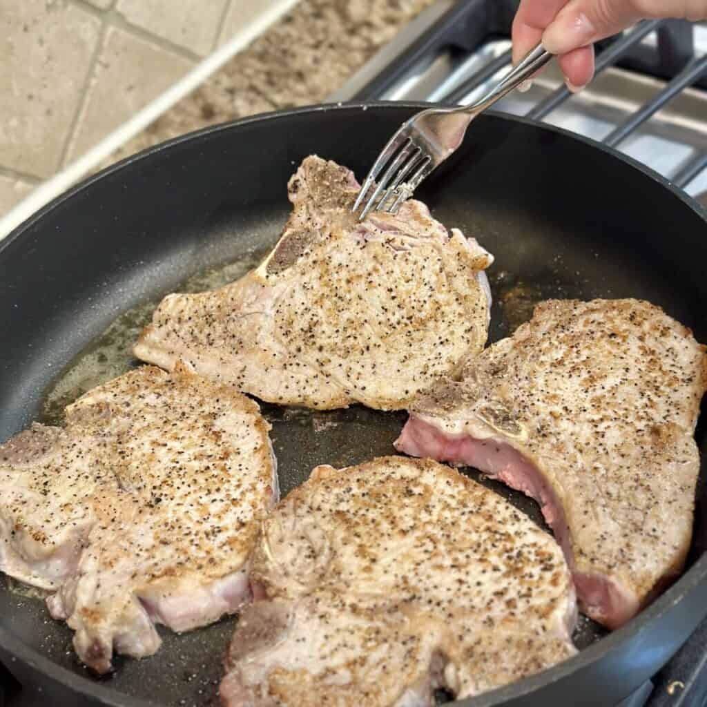 Searing pork chops in a skillet.