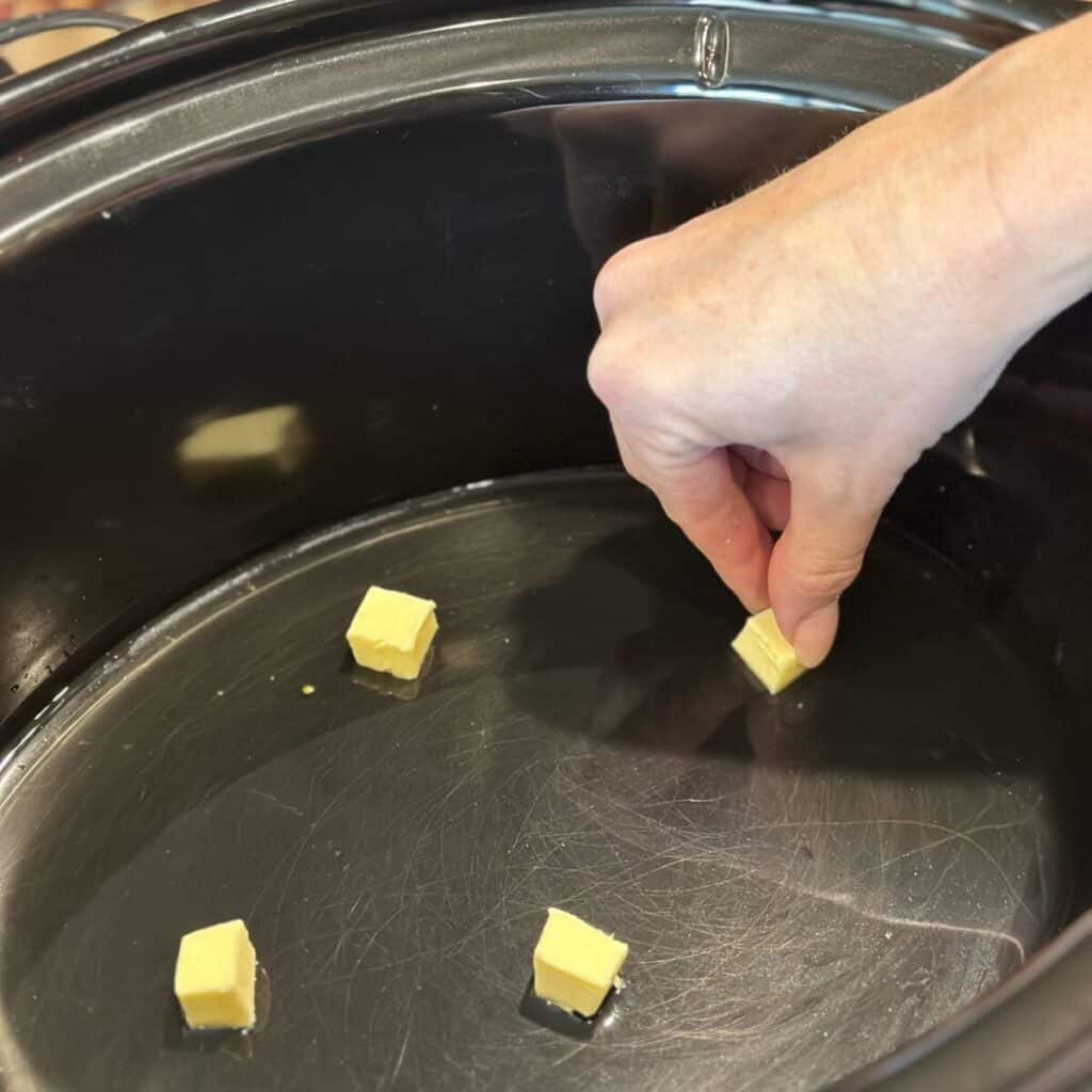 Adding butter and broth to a crockpot.