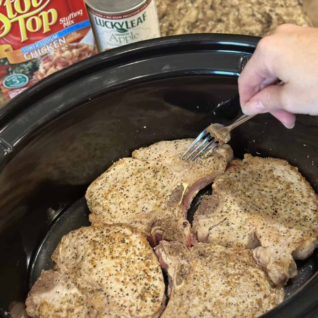 Adding pork chops to a crockpot.