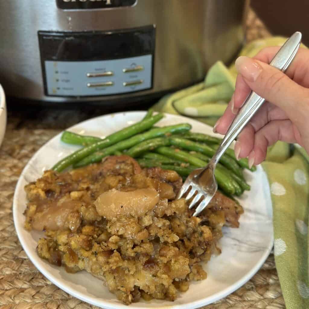 Slow cooker pork chops and apples on a plate with green beans.