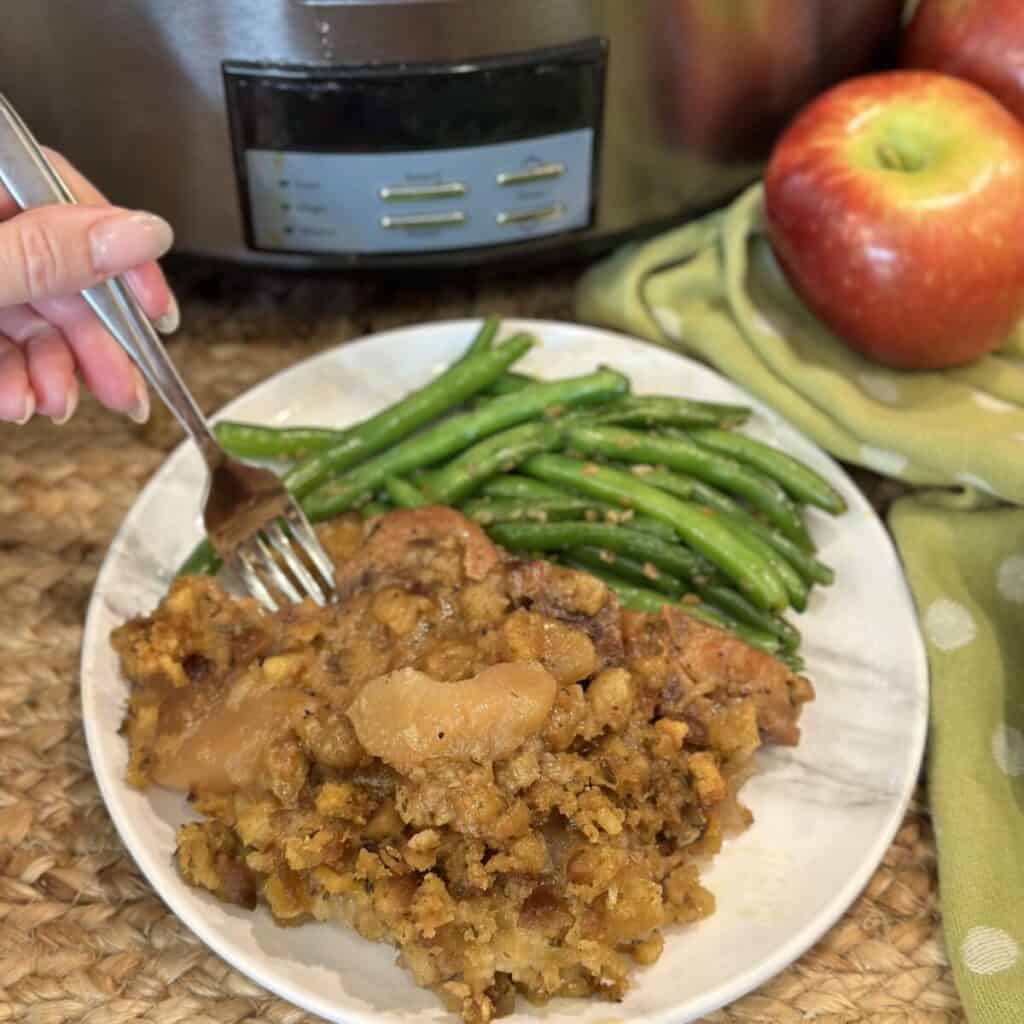 Slow cooker pork chops and apples on a plate with green beans.