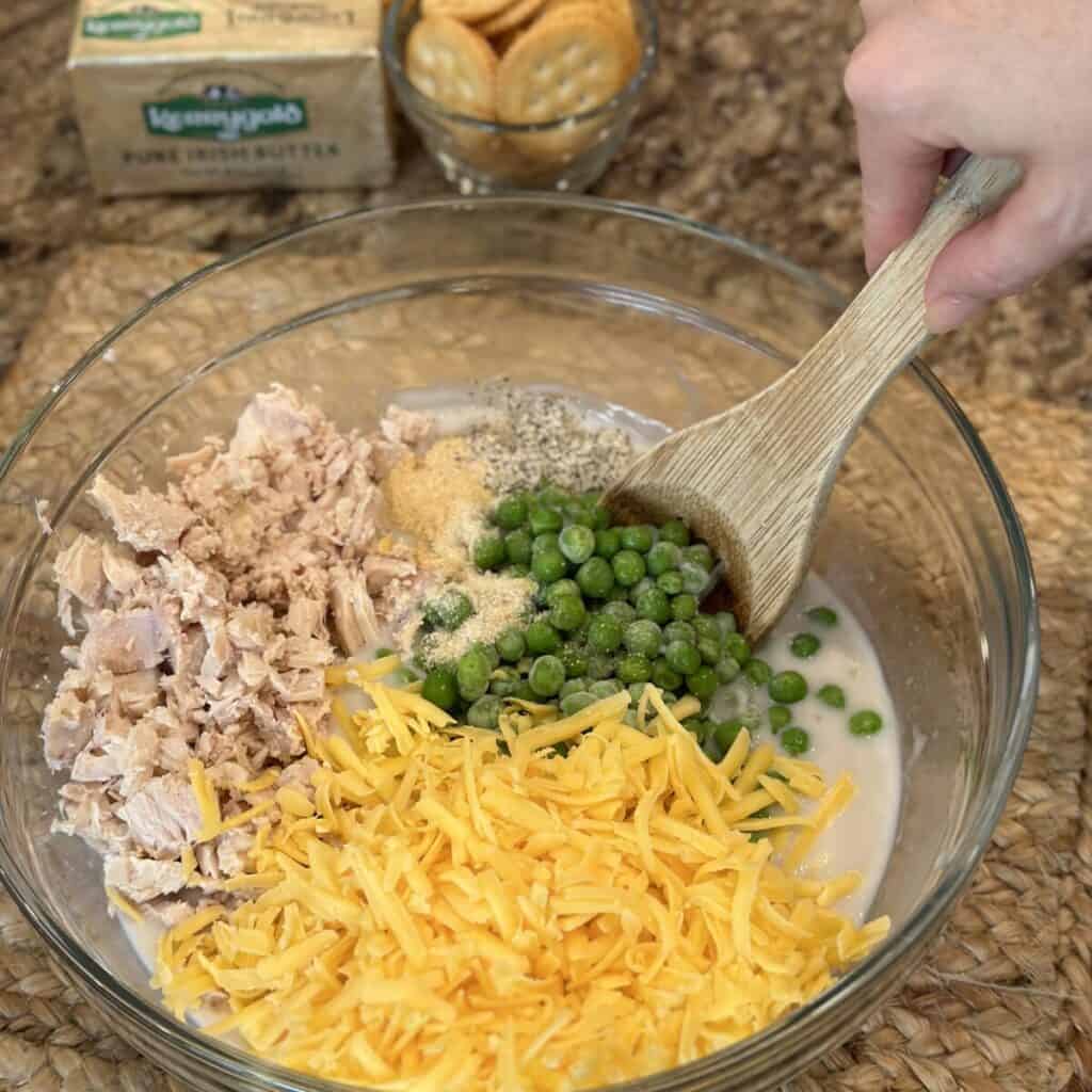 Mixing the filling for tuna noodle casserole in a bowl.