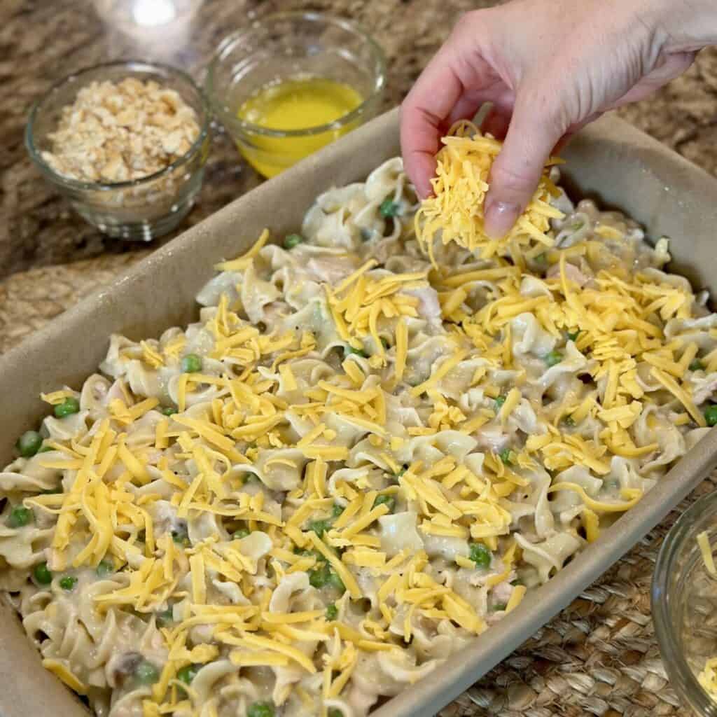 Sprinkling cheese on tuna noodle casserole.