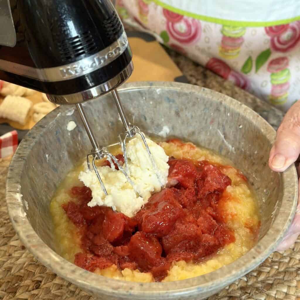 Mixing cream cheese, strawberries and pineapple together.