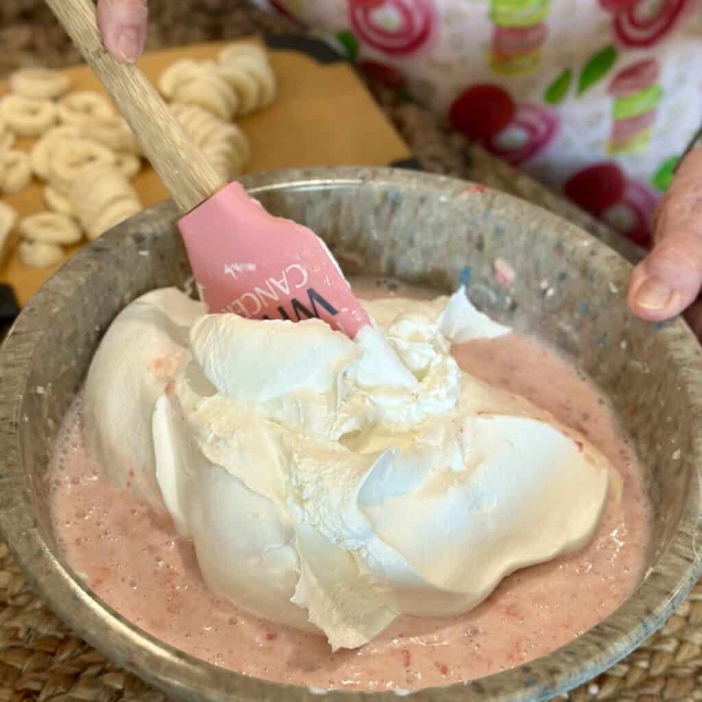 Folding cool whip in a fruit salad.