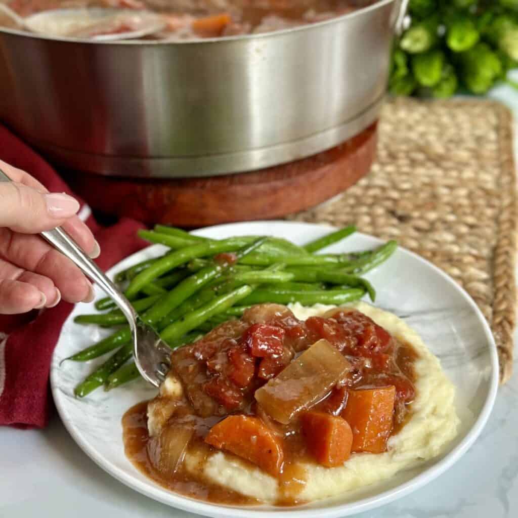 Swiss steak, mashed potatoes and green beans on a plate.