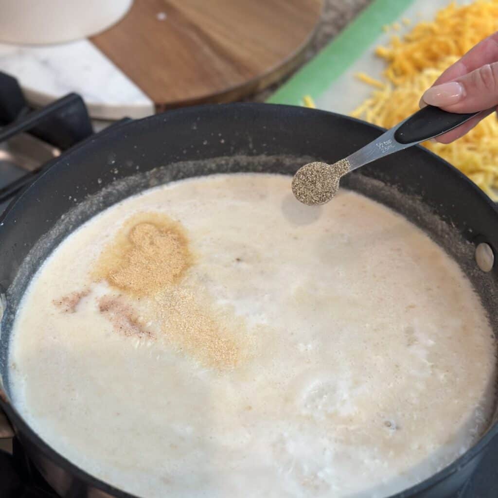 Adding seasoning to a cheese sauce.