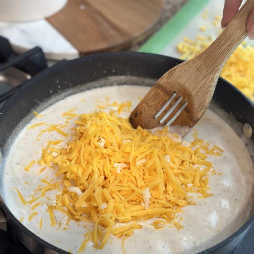 Adding cheese to a cheese sauce base.