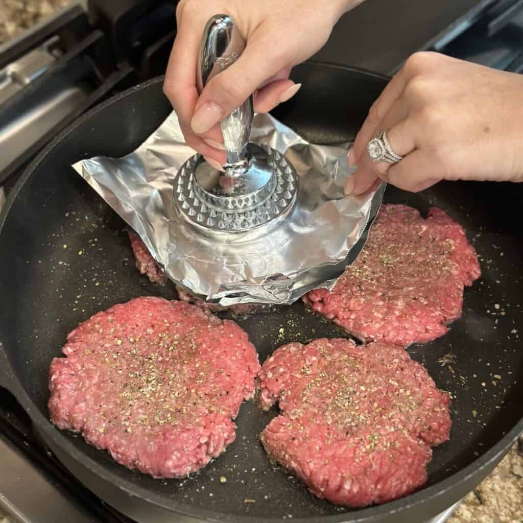 Pressing burgers in a skillet.