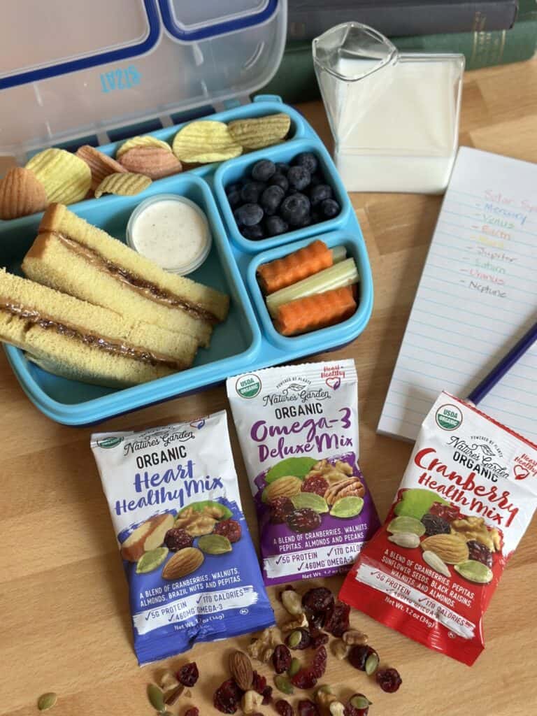 Three packs of trail mix that are healthy snacks for kids next to a lunch box.