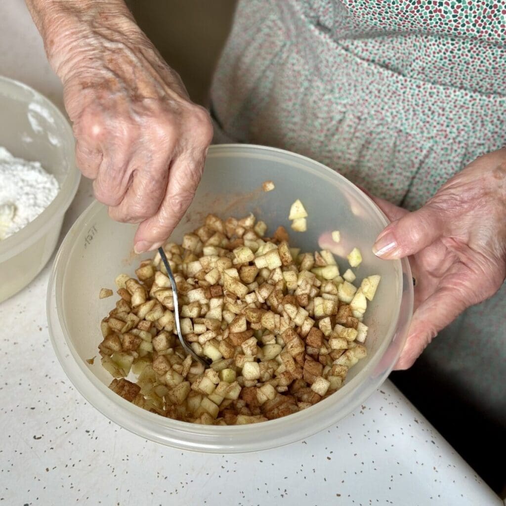 Mixing chopped apples with cinnamon in a bowl.