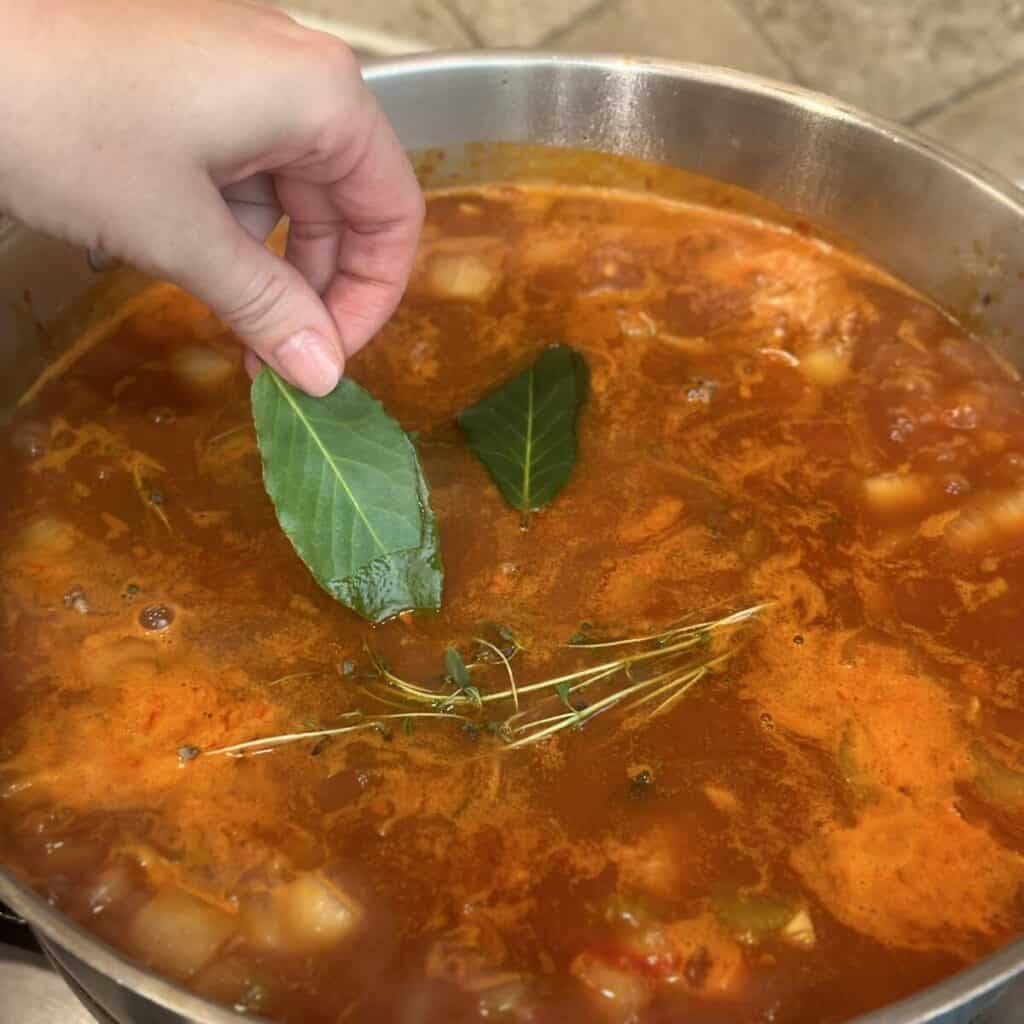 Adding herbs to beef stew in a pan.