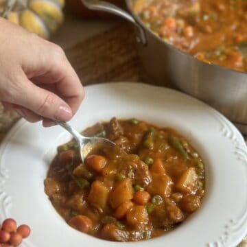 A spoon in a bowl of vegetable beef soup.