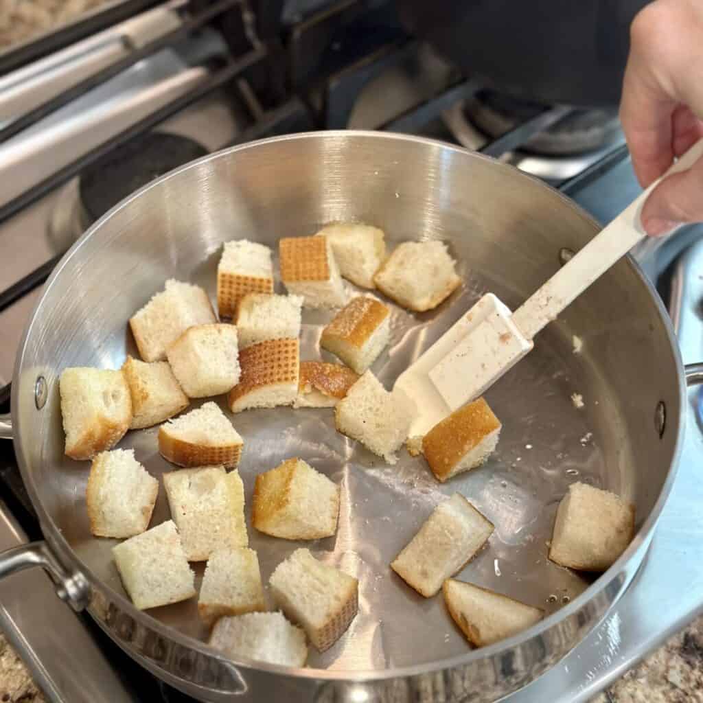 Toasting bread cubes in a pan.