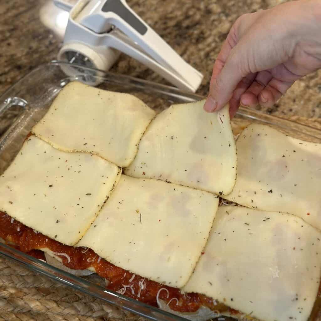 Adding the mozzarella layer to meatball casserole.