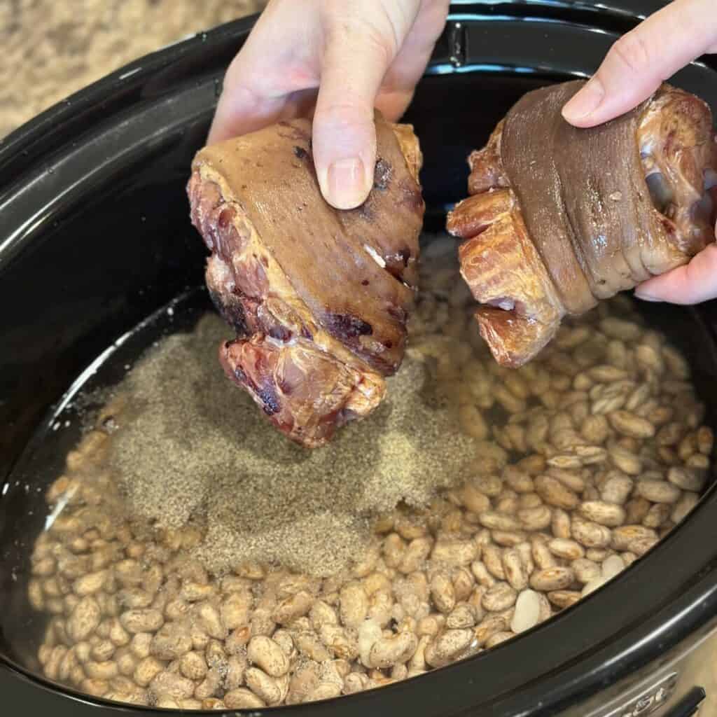 Adding ham hocks to pinto beans in a crockpot.