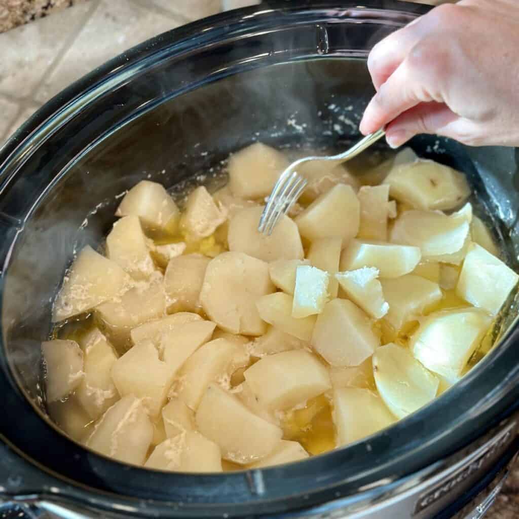 Checking potatoes for doneness in a crockpot.