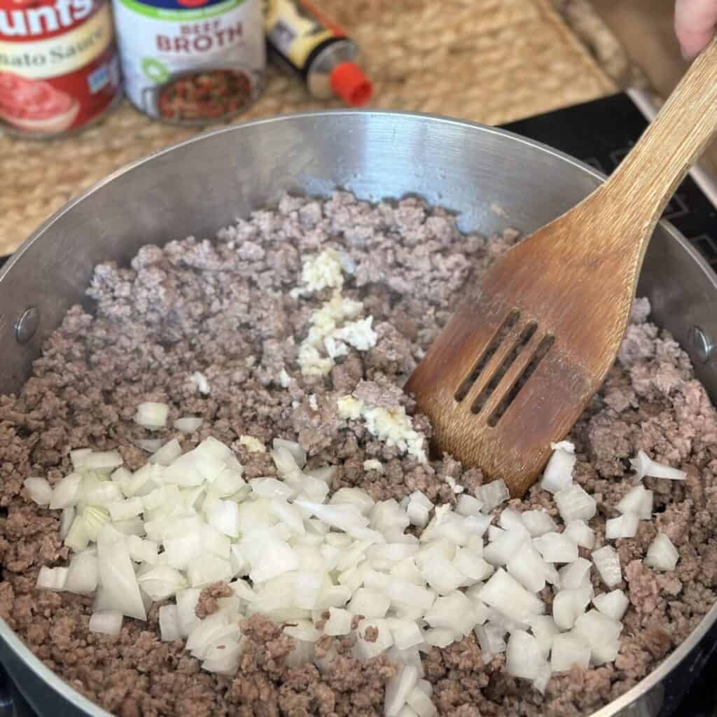 Cooking ground beef and onions in a skillet.