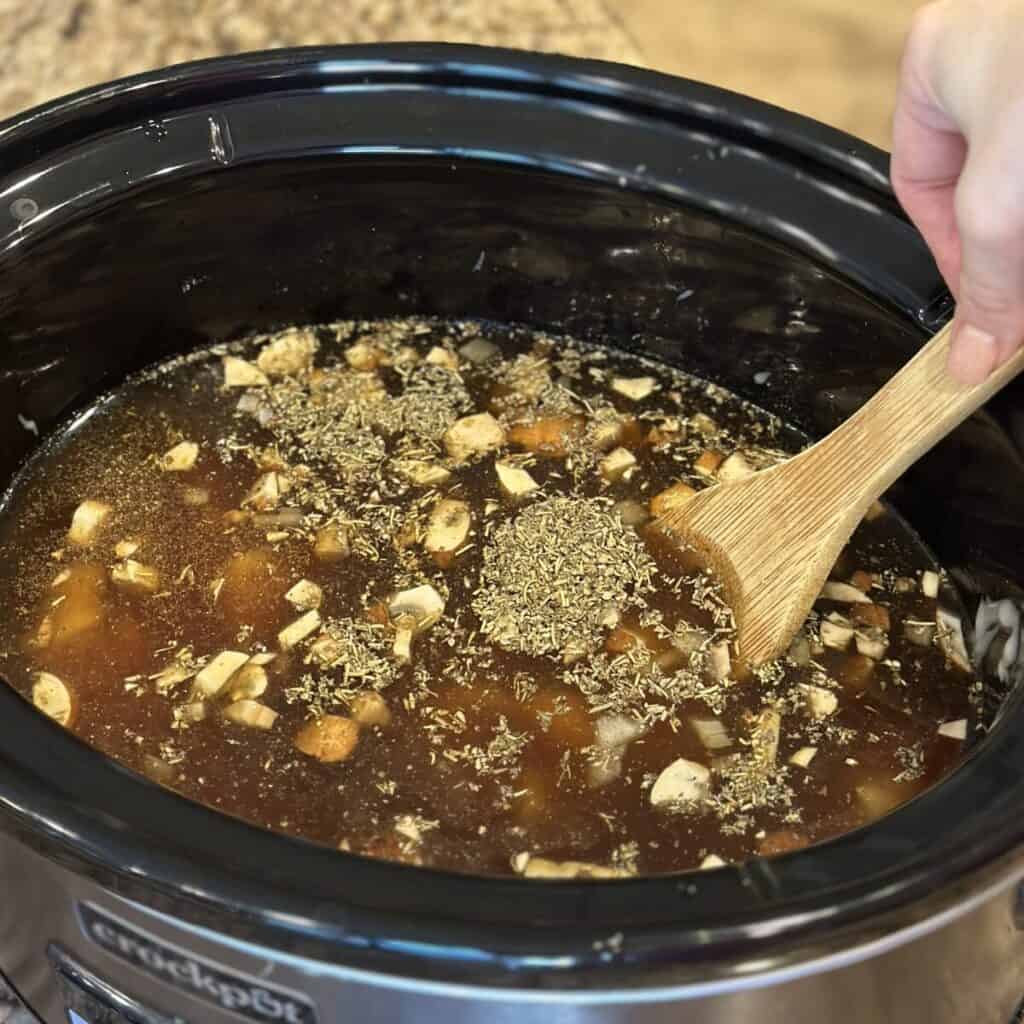 Mixing the seasoned beef broth in a crockpot for beef.