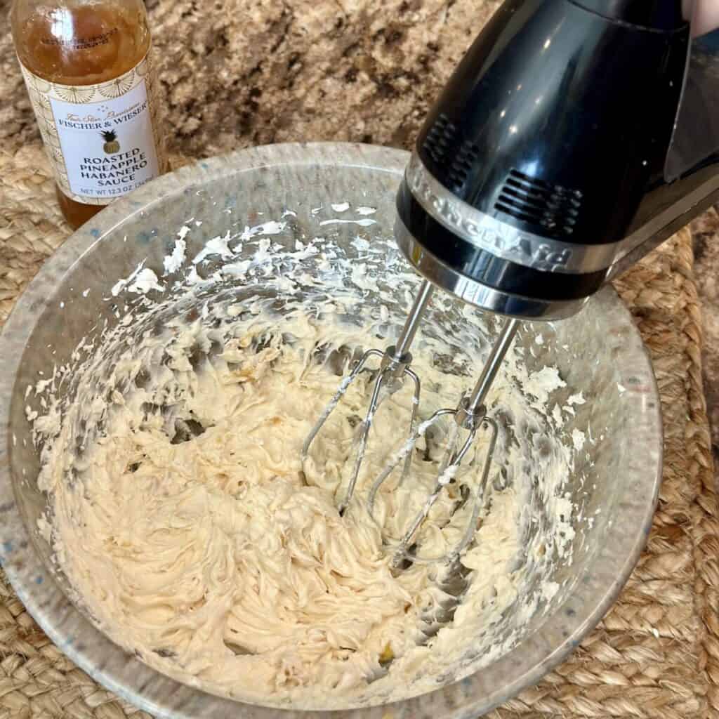 Whipping cream cheese in a bowl with pineapple jelly.