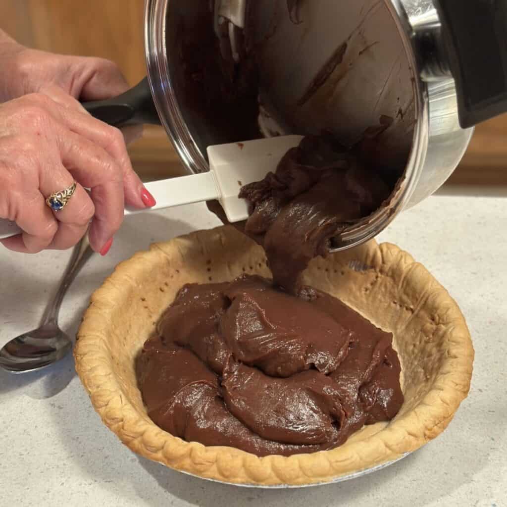 Adding chocolate filling to a pie shell.