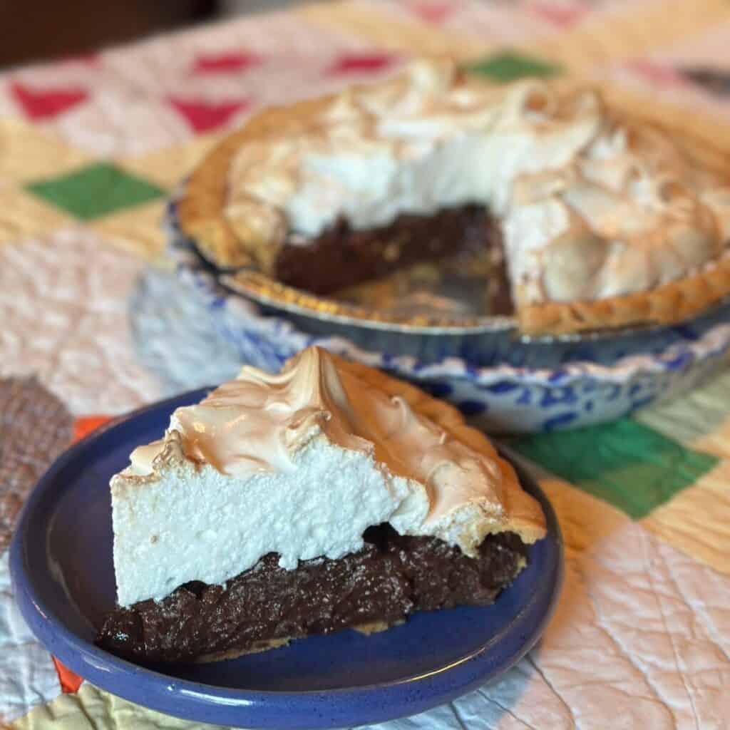 A chocolate meringue pie and a slice on a plate.