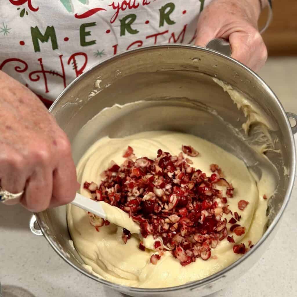 Folding chopped cranberries into a pound cake batter.