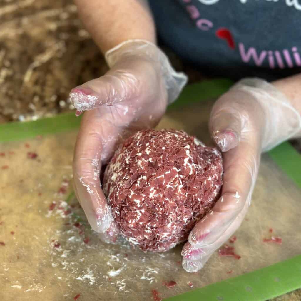 Rolling a cheeseball in dried beef.