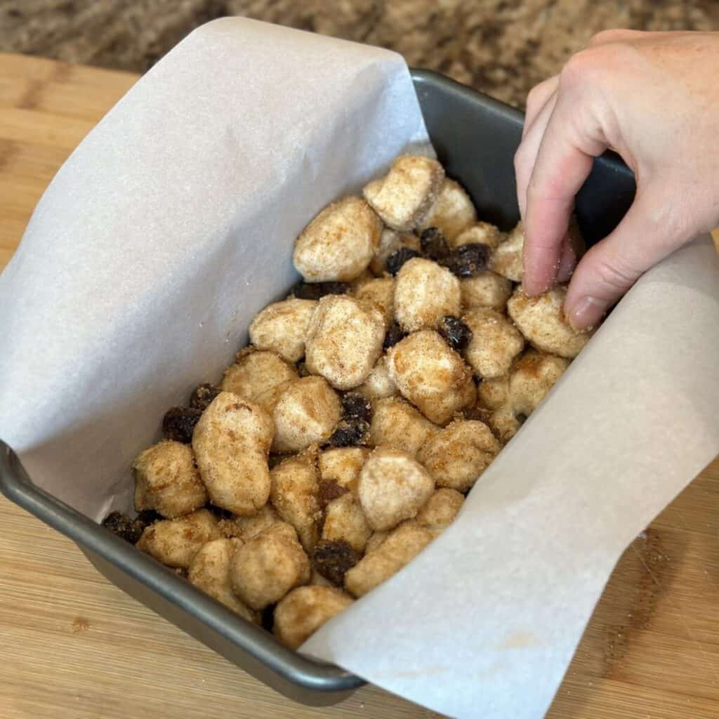 Adding biscuit dough to loaf pan.