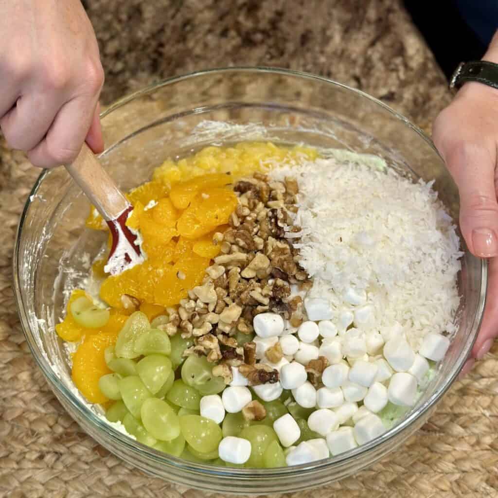 Blending together the ingredients in a bowl of pistachio ambrosia salad.