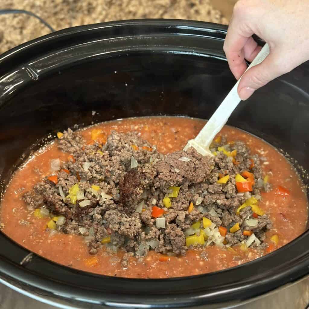 Combining ingredients in a skillet for slow cooker hamburger helper.