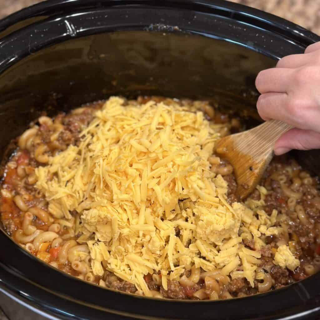 Adding cheese to a crockpot for slow cooker hamburger helper.