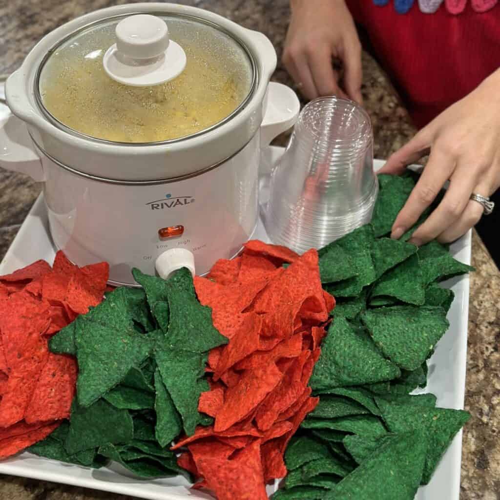 Laying tortilla chips on a serving tray with dip.