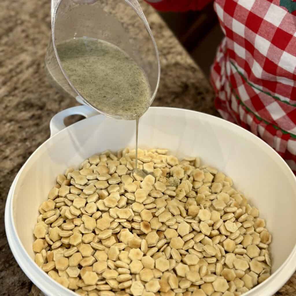 Pouring the seasoned oil blends on crackers for ranch dill oyster crackers.