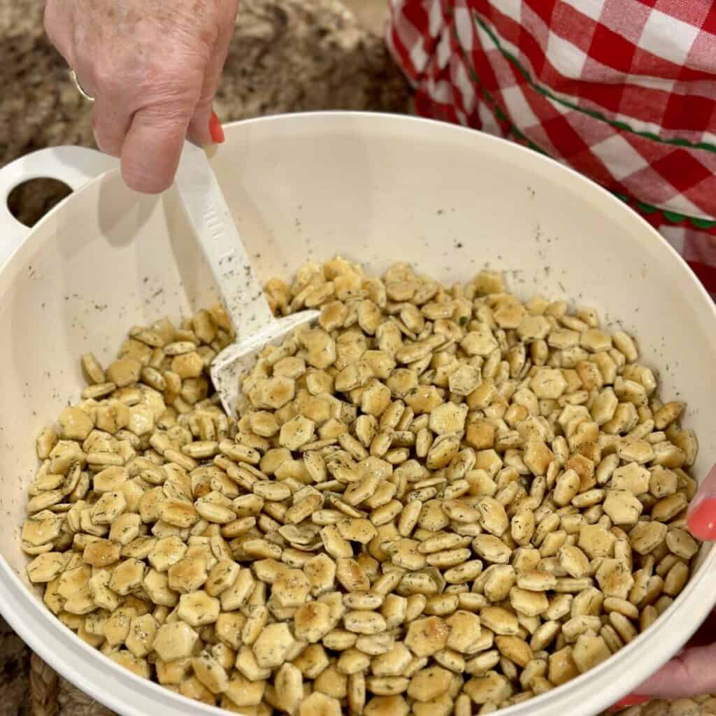 Stirring ranch dill oyster crackers in a bowl.