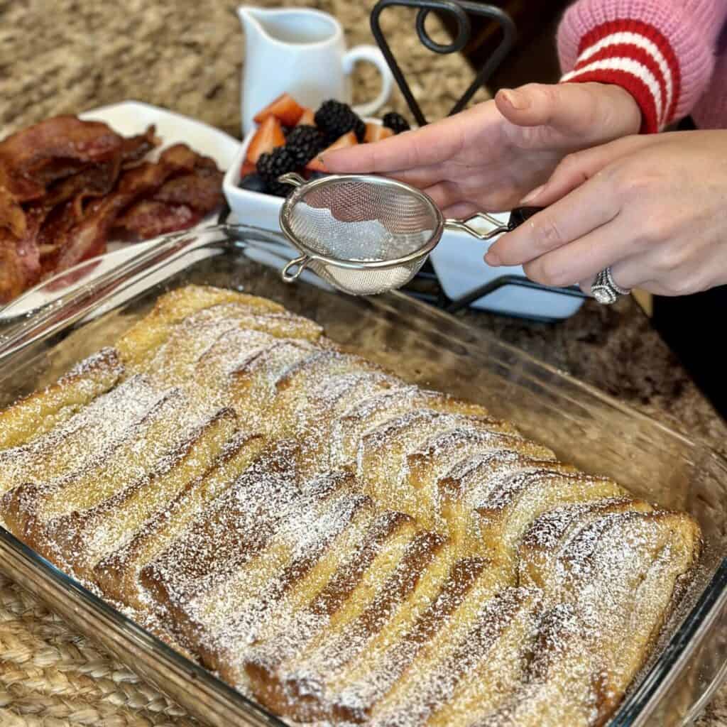 Sprinkling powdered sugar on french toast.