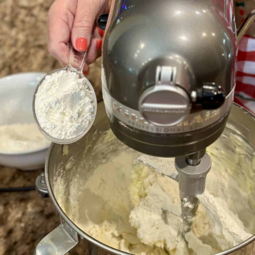 Adding powdered sugar to cookie dough batter in a mixer.