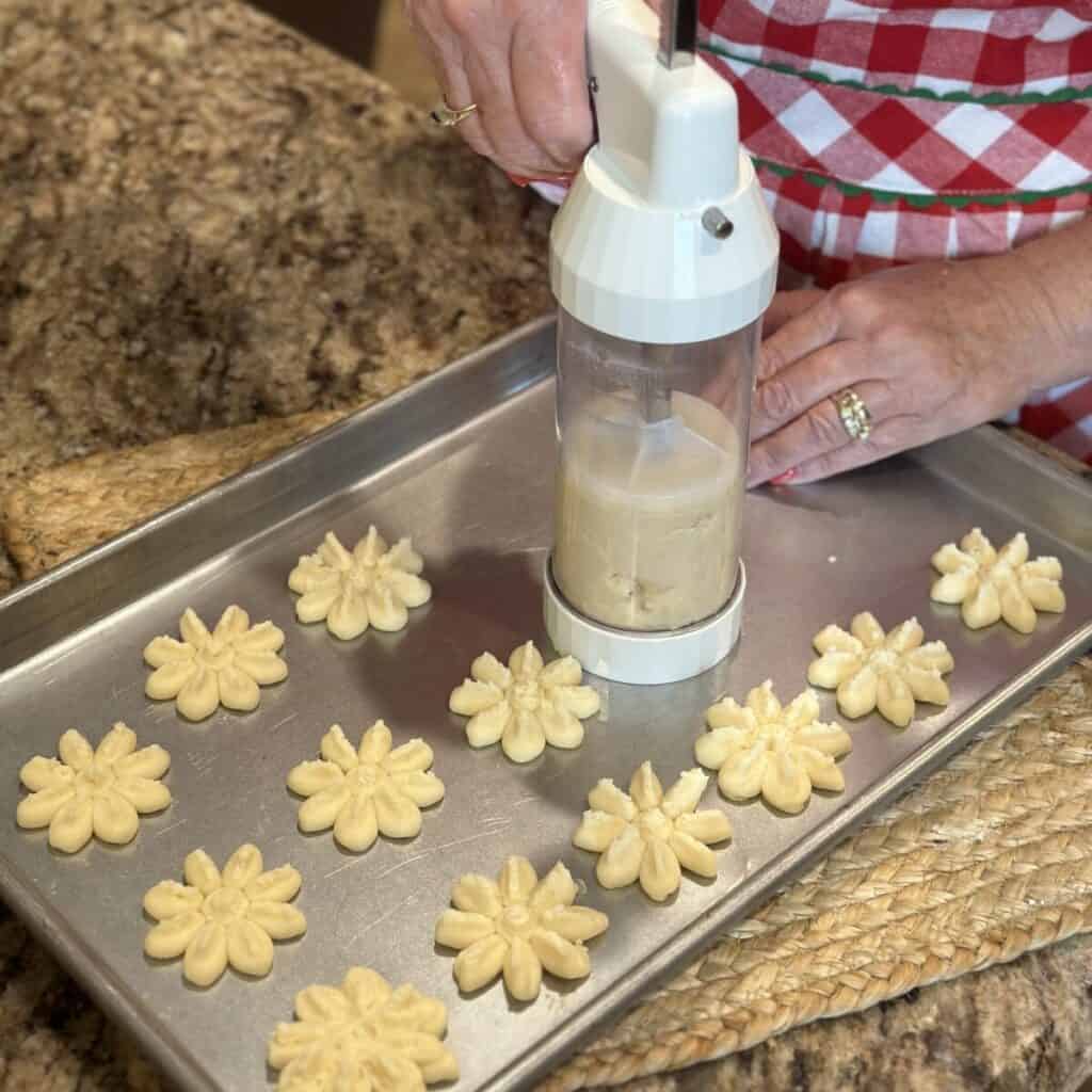 Pressing shortbread cookies on a sheet pan.