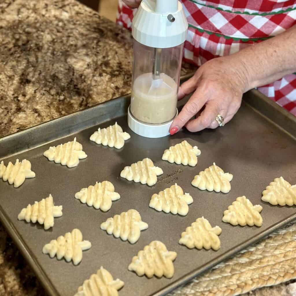 Pressing shortbread cookies on a sheet pan.