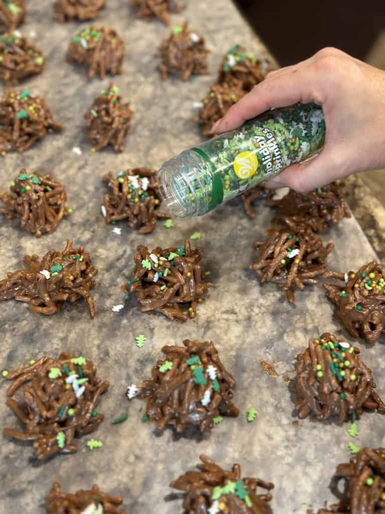 Adding sprinkles to haystack cookies.